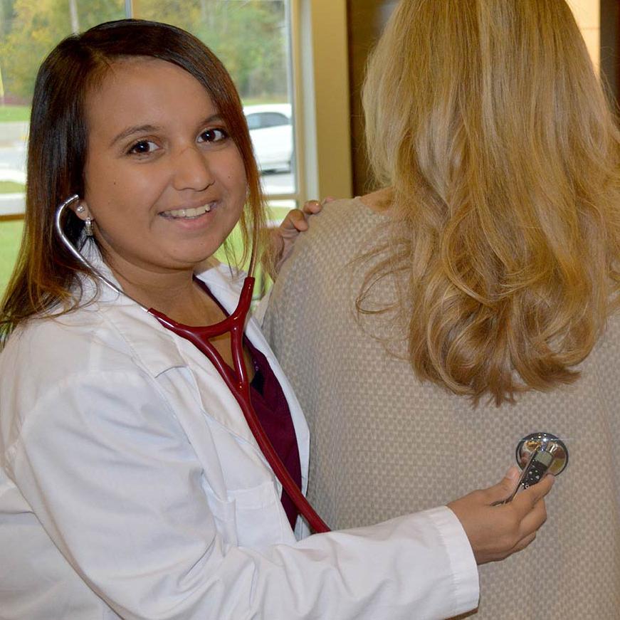 A health sciences student wearing a hearing aid using a stethoscope  